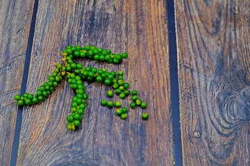 Organic fresh green peppercorns on wooden table.