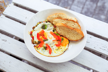 Smażone jajka, omlet, potrawa na śniadanie, biały talerz, dodatki sałatka i warzywa oraz pieczywo.