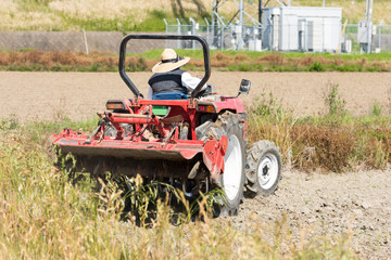 Obraz premium Red tractor plowing the rice field farmland. 