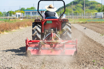Obraz premium Red tractor plowing the rice field farmland. 