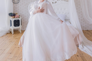 Fototapeta na wymiar the bride in a peignoir holds a wedding dress