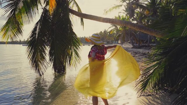 Girl enjoying sunrise over tropical island beach with palm trees