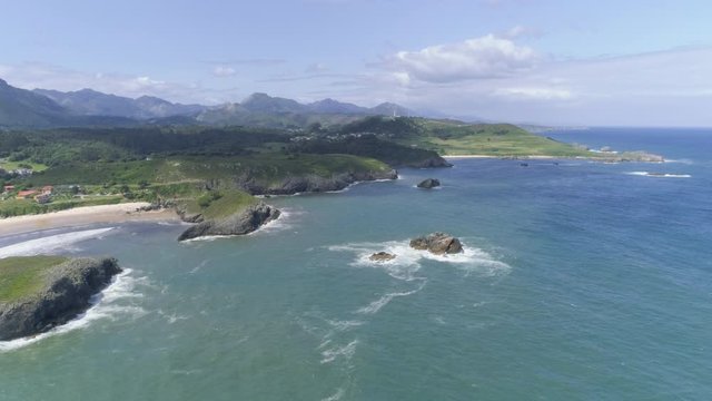 AERIAL DRONE SMOOTH FORWARD SHOT OF NORTHERN SPAIN CLIFF COAST WITH BLUE SEA AND MOUNTAIN RANGE BACKGROUND