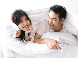 Happy Asian couple under blanket on bed together, lifestyle concept.
