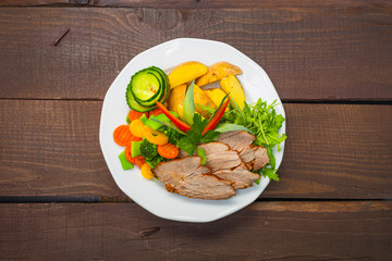 Fototapeta Zdrowy lunch lub obiad, serwowany na białym talerzu na ciemnym drewnianym stole. obraz