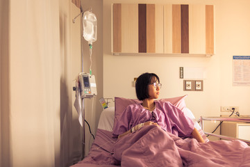 A sick girl in a purple striped suit with life support equipment on a hospital bed - Powered by Adobe