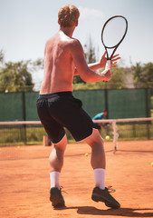 A man plays tennis on the court in the park.