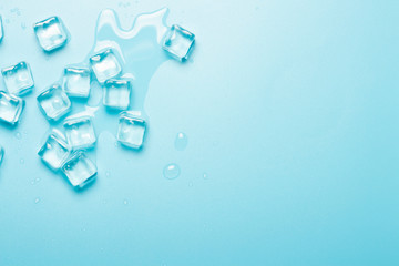 Ice cubes with water on a blue background. Ice concept for drinks. Banner. Flat lay, top view