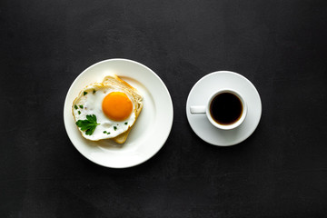 Fried eggs sandwich on plate - black dinner table top view
