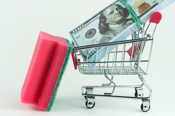 sponge for washing dishes and a grocery cart with money, concept of money laundering