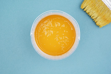 Paintbrush and bucket of ocher paint,top view.  Brush and paint on blue background
