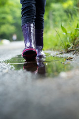 un enfant marche dans une flaque d'eau en botte