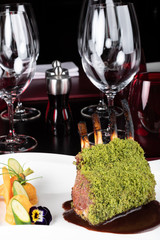 Piece of lamb rack with bone roasted with green herb, bread, sweet potatoes puree, baby vegetables