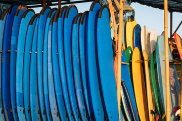 Close up stack of blue color soft surfboards in a stack by ocean.Bali.Indonesia. Surf boards on sandy beach for rent. Surf lessons on Weligama beach, Sri Lanka.