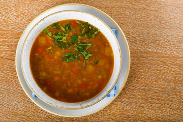 Fresh lentil soup in a white bowl, served in a restaurant setting, selective focus.
