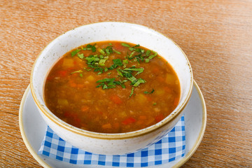 Fresh lentil soup in a white bowl, served in a restaurant setting, selective focus.