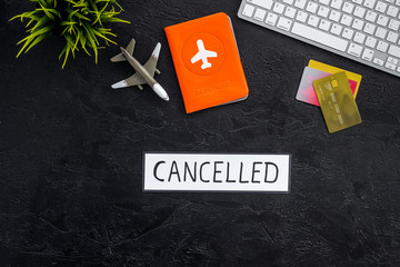 Cancelled flight. Airplane and passport on black background top view