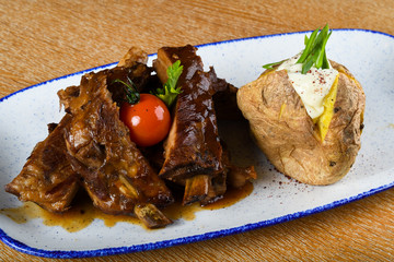 Spicy hot grilled spare ribs from a summer BBQ served with a hot chili pepper and fresh tomatoes