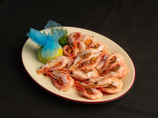 Serving of prawns on an oval plate with lemon and spices
