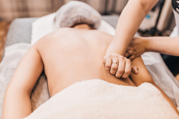 Treatment of pain in the spine with massage - hands of a masseur on the patient back - manual therapy