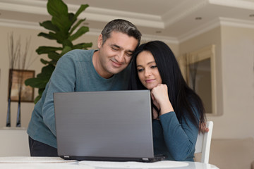 Couple working at home together using laptop
