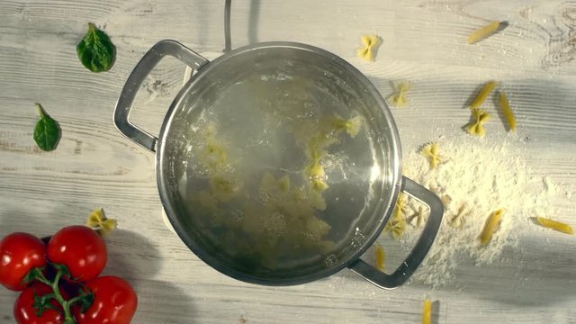 SLOW MOTION: throw a pasta in a steel pan. Top view. Shot with cinema camera RED DRAGON 240 fps.