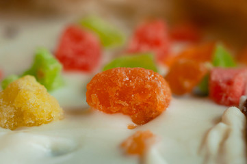 Orange slice of confectionery marmalade decorating white icing baking, close-up.