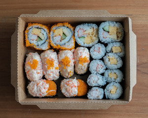 Bento box set of Sushi, California roll, Maki sushi roll. Japanese food in A Single portion takeout or take home meal in paper food box package. Environmentally-friendly food box for takeaway.
