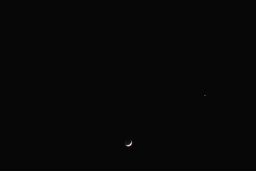 Young Moon and Venus on a dark night sky.