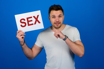 Handsome stylish man standing with a sign in his hand in the studio on a blue background. Cool.