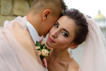 The bride and groom are hugging. Focus on the bride. A woman is looking into the frame. The girl smiles into the frame. Close-up shot.