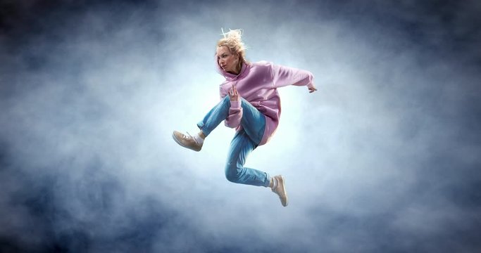 Female street dancer in a jump with fog on a backgroung.