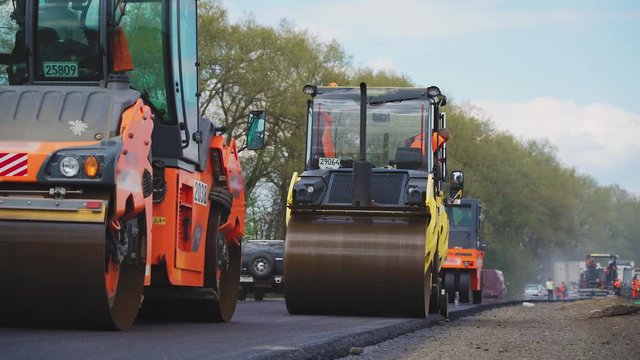 Roller machines make new asphalt roads. The asphalt paver squeezes hot asphalt.