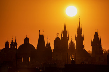 Silhouettes of Prague towers at sunrise.
