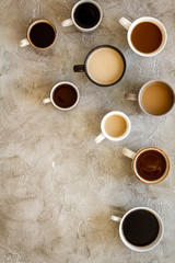 Different cups of coffee on beige table top-down space for text