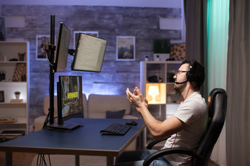 Side view of professional shooter gamer clapping after his victory on an important online...