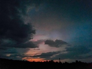 Fototapeta premium sunset coloring the clouds among the trees