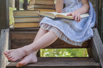 Summertime fun. Cute Blond Girl Reading Book Outside on Grass