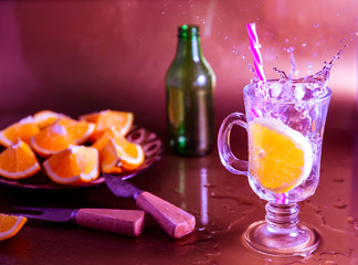 alcohol cocktail with ice and lime. splash in a transparent drink. a glass with a slice of orange. splash of homemade refreshing lemonade with orange