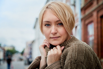 Blonde funny pretty girl near wall with red brick in Central part of old city. Portrait of girl on street