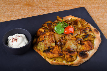 Baked chicken tights and breast served on a pita bread or focaccia pizza dough, restaurant setting