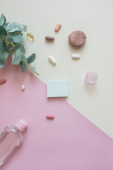 A close-up top view of various pills, macaroni  and antiseptic on pink and yellow background. Dietary supplements and vitamins. Copy place for text or logo. Medical, pharmacy and health care concept.