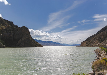 Buffalo Bill Reservoir view near big rocks and blue sky in United States. Coastline near lake un national park with nature landscape and concept of travel attraction in Wyoming on way to Yellowstone