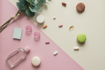 A close-up top view of various pills and macaronis on pink and yellow background. Dietary supplements and vitamins. Medical, pharmacy and health care concept. Copy place for text or logo. Top view
