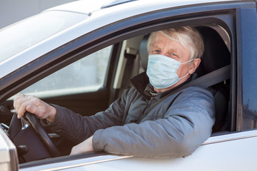 Portrait of an elder car driver wearing medical mask to prevent coronavirus infection