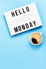 Text "hello monday" on lightbox and cup of coffee for holiday - Thank God It’s Monday. Start of working week concept. Top view on blue background.