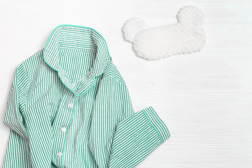 Sleepwear for slumber. Women neo mint colored pajama with stripes and sleeping mask on white wood....