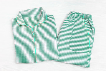 Folded pajama with striped neo-mint color on white wooden surface with copy space. Night suit for...