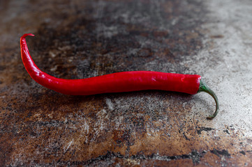 Red spicy pepper on dark worn rusty metal texture background.