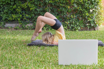Pre teen girl practicing gymnastics at home, watching online video on laptop. Social distance, online education concept. Healthy lifestyle, coronavirus, stay home. Kids sport home quarantine.
